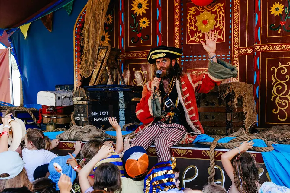 a pirate is on stage with a crowd of children raising their hands