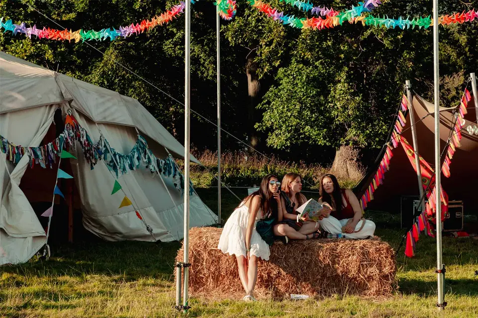 three teenagers are sat on a hay bale