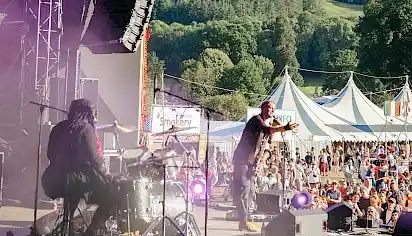 A band performing on stage at Green Man festival, surrounded by cheering fans