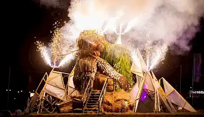 The start of Green Man burn. The Green Man sculpture made of wood and leaves is asleep as fireworks erupt around him
