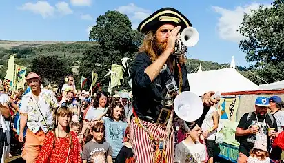 A pirate playing a trumpet leads a parade of children
