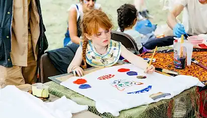 A girl concentrates on painting a tiger, she has an ancient egyptian necklace on