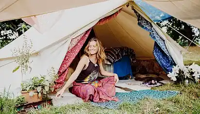 A woman sits outside her tent with plants