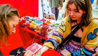 A teenager gets her hand painted with henna