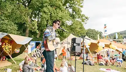 A boy sings and plays guitar on the Somewhere busking stage