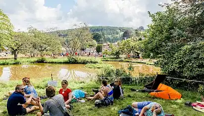 People sit on the grass around the lake