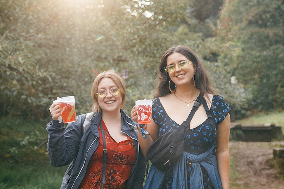 Two women smile and hold their drinks up
