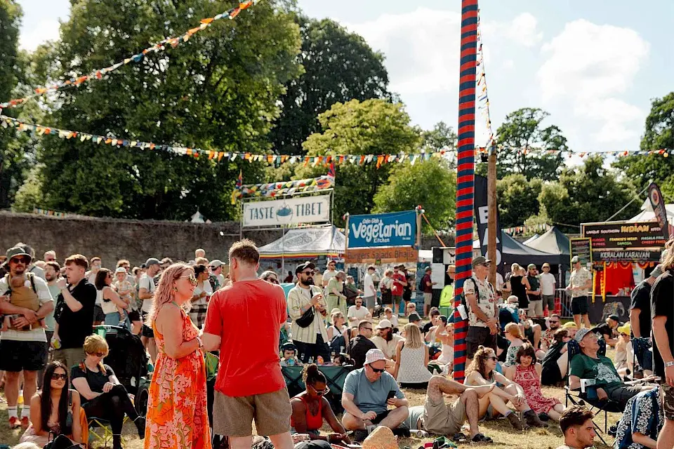 groups sit in the walled garden in front of food traders, there is bunting above them