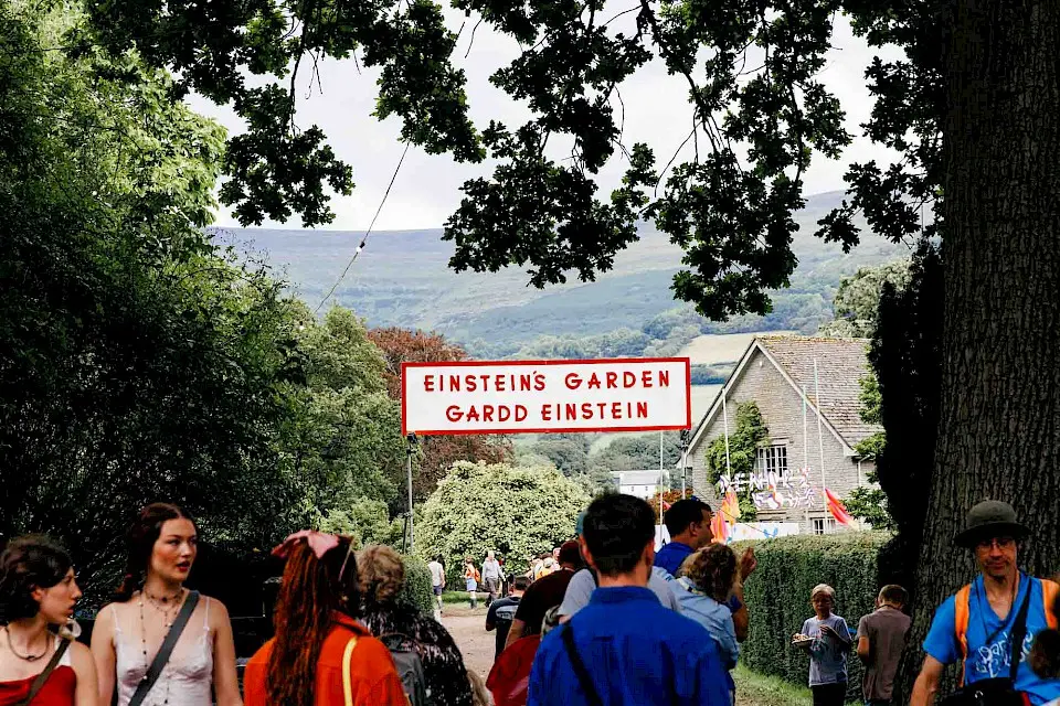 people walk underneath a sign for Einstein's Garden