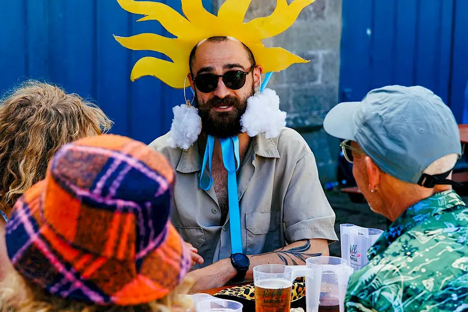 a man dressed as the sun sat enjoying a pint