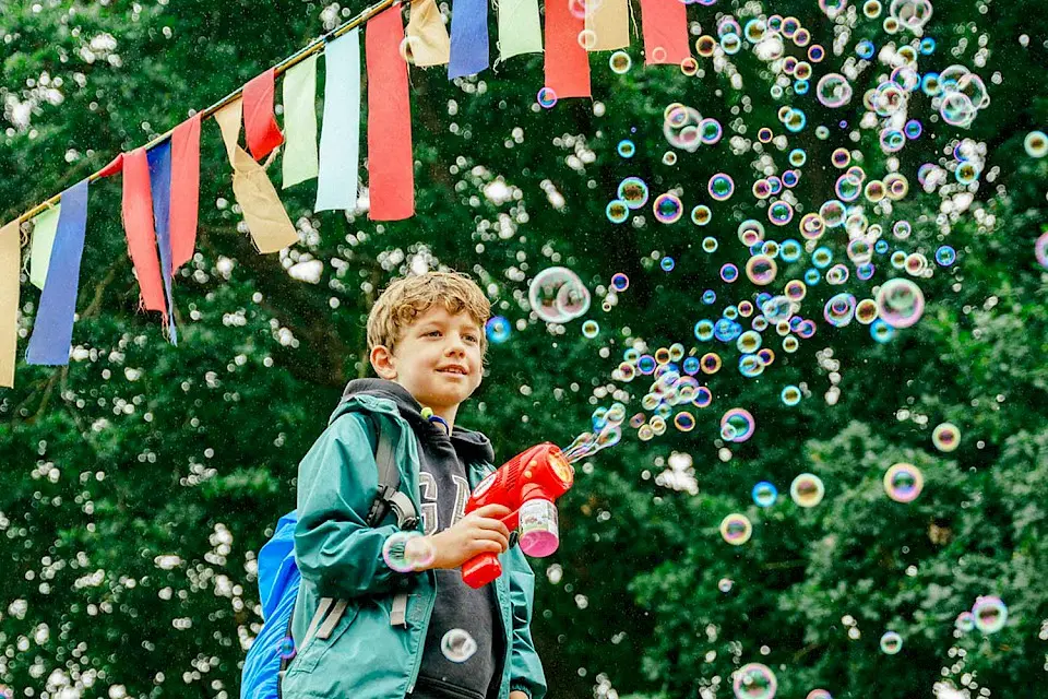 a boy is using a bubble gun under some bunting