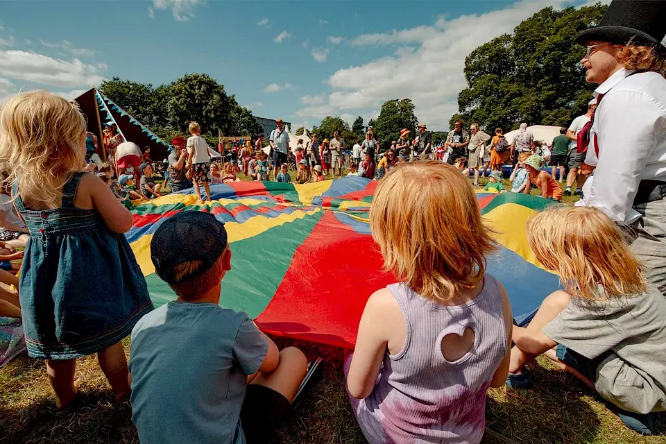 children gather around a brightly coloured parachute