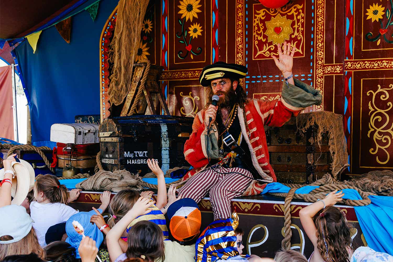 a pirate is on stage with a crowd of children raising their hands
