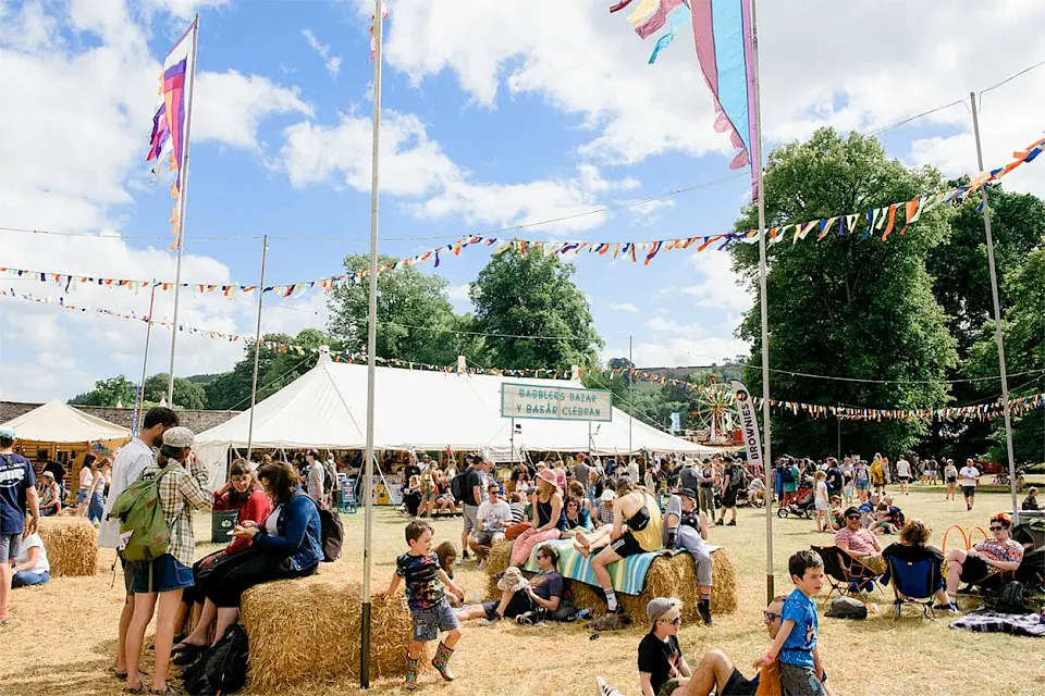 people sat on hay bales beneath bunting and large festival flags