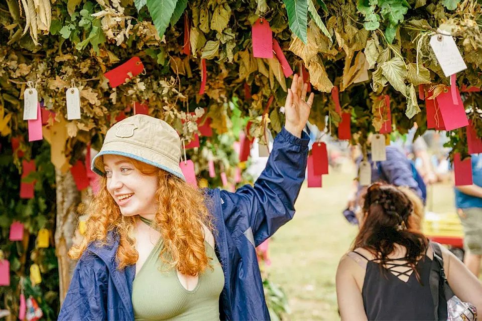 a girl in a bucket hat adds her wish to the green man