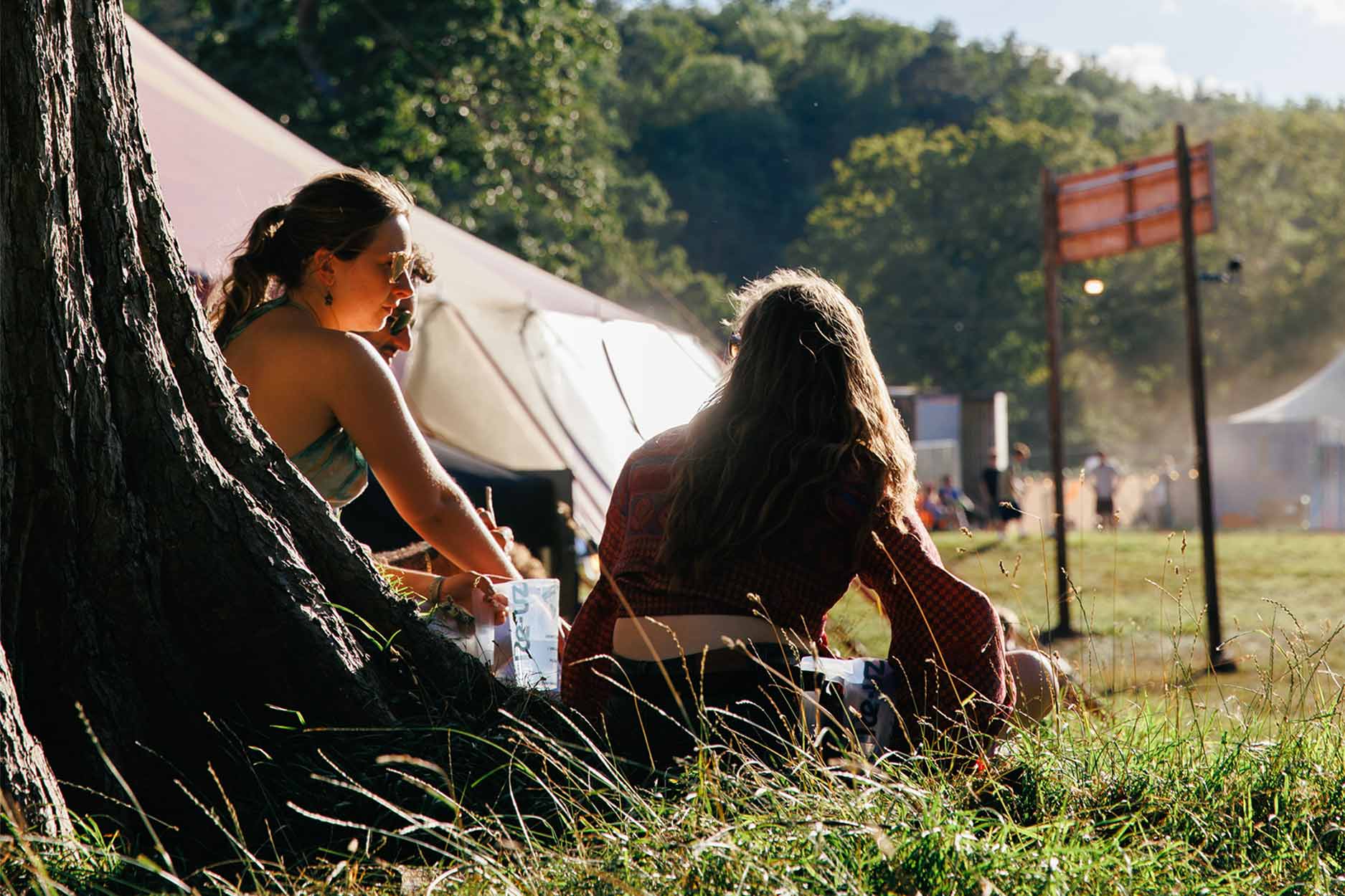 two women are sat underneath a tree relaxing