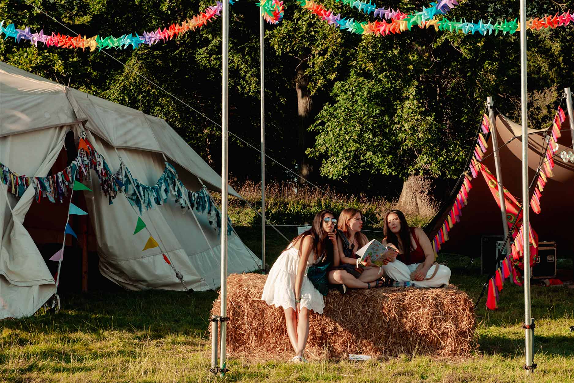 three teenagers are sat on a hay bale