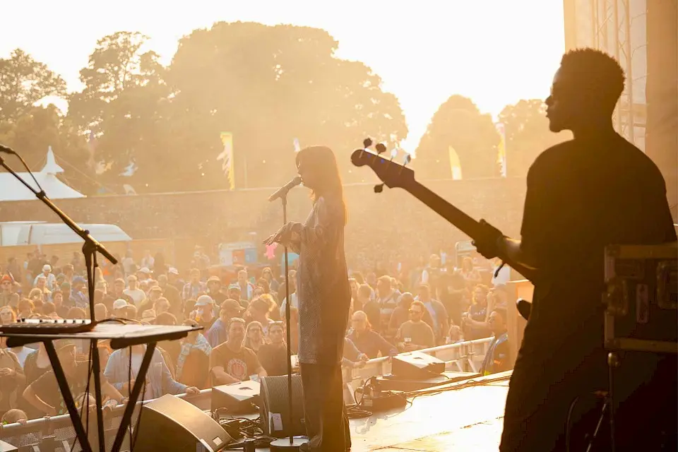 a singer performing on the walled garden stage as the sun sets