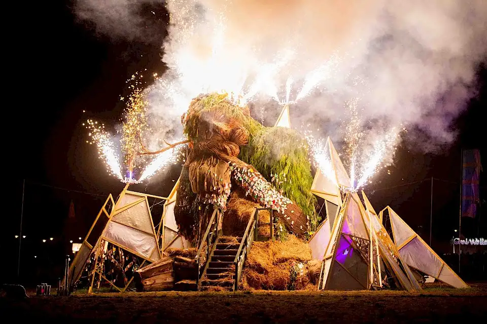 The start of Green Man burn. The Green Man sculpture made of wood and leaves is asleep as fireworks erupt around him