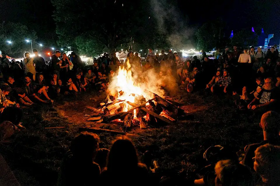 A crowd gathers around the bonfire in the Far Out field