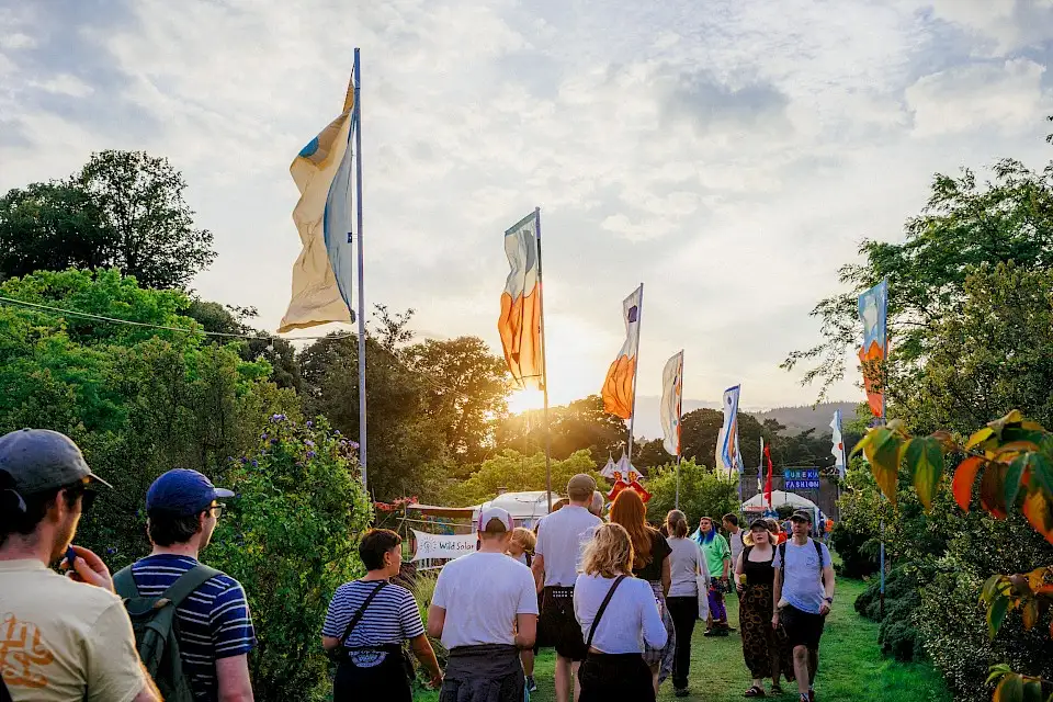 People walk towards the sunset along a flag lined walkway