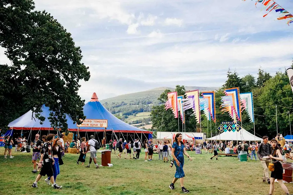 Babbling Tongues area, there is the Babbling Tongues tent which is a large blue and red circus style tent, the Babbler's Bar and large multicoloured festival flags