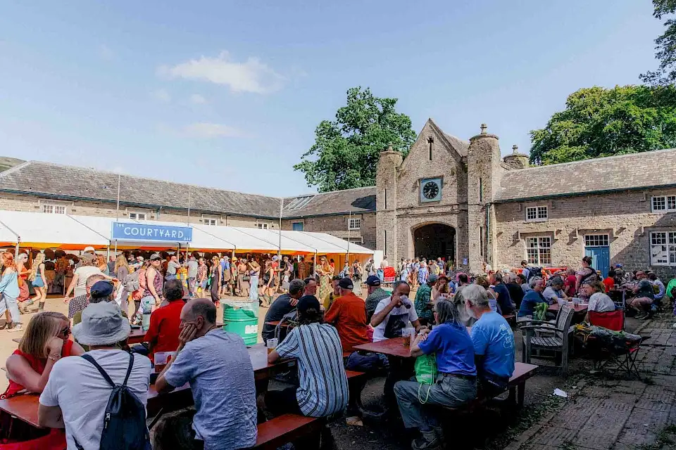 The Courtyard beer festival, large groups of people sit at picnic benches enjoying the sunshine and drinks