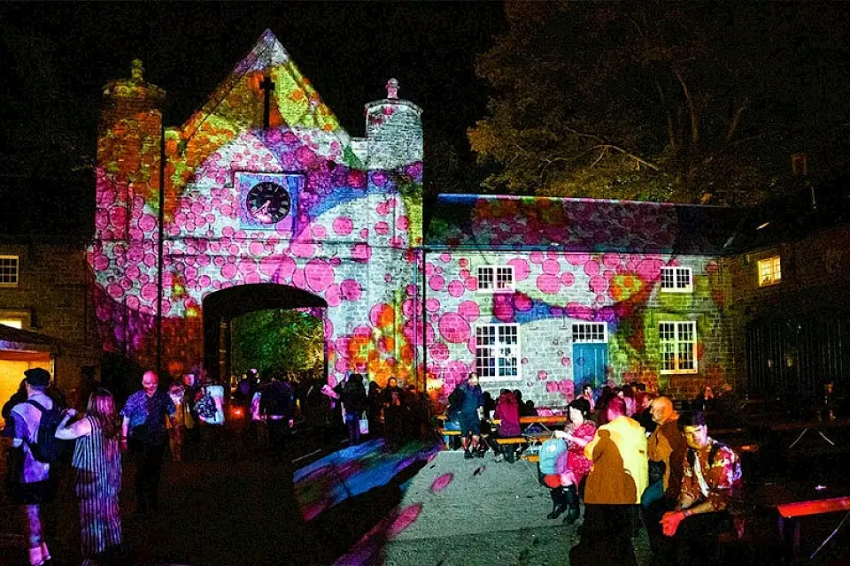 The Courtyard Building lit up by a patterned light desing with pink and yellow spots