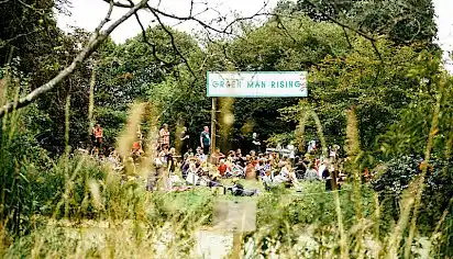 The sign for 'Green Man Rising' amongst the trees and across a small lake