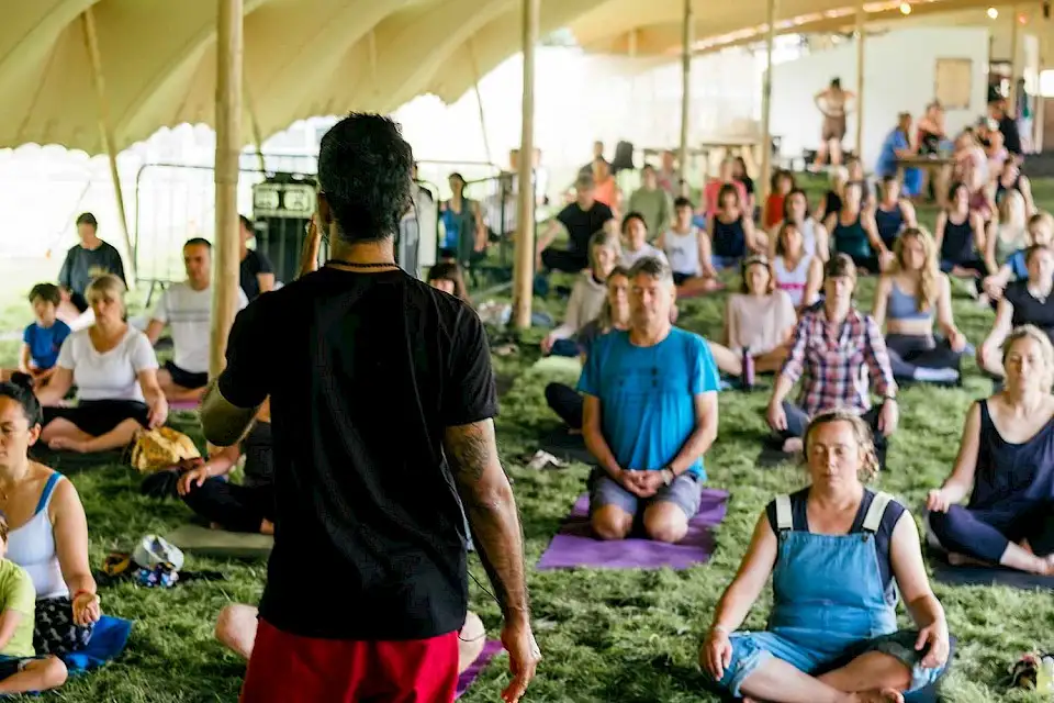 A man leads a large group of people in a yoga session