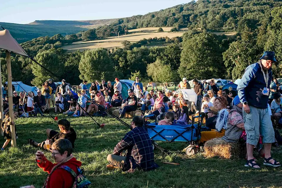 Groups sit on hale bales in fron of the Acoustic stage in the sunshine