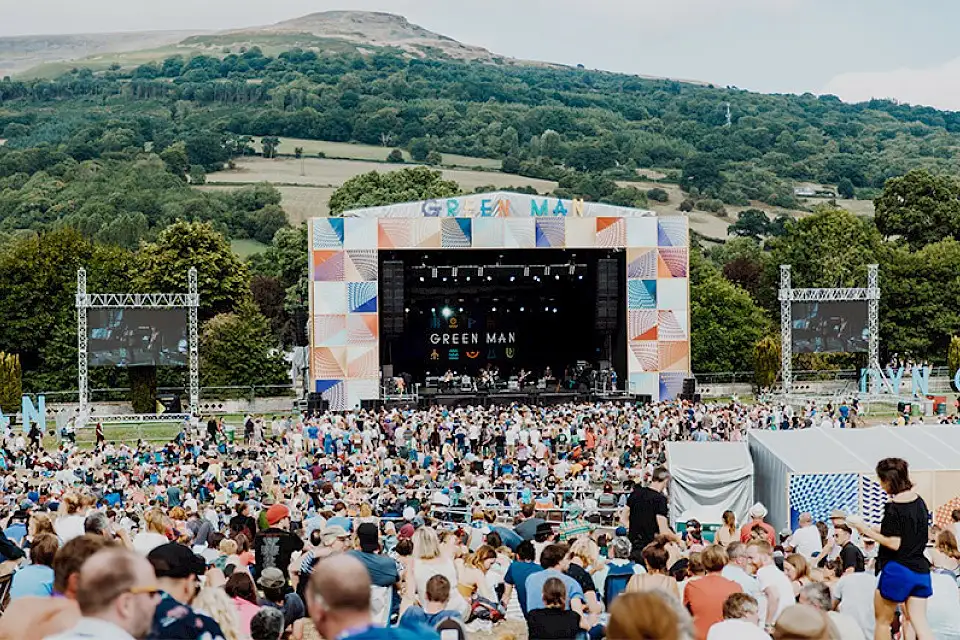 The mountain stage in front of the black mountains with a large crowd in front of it