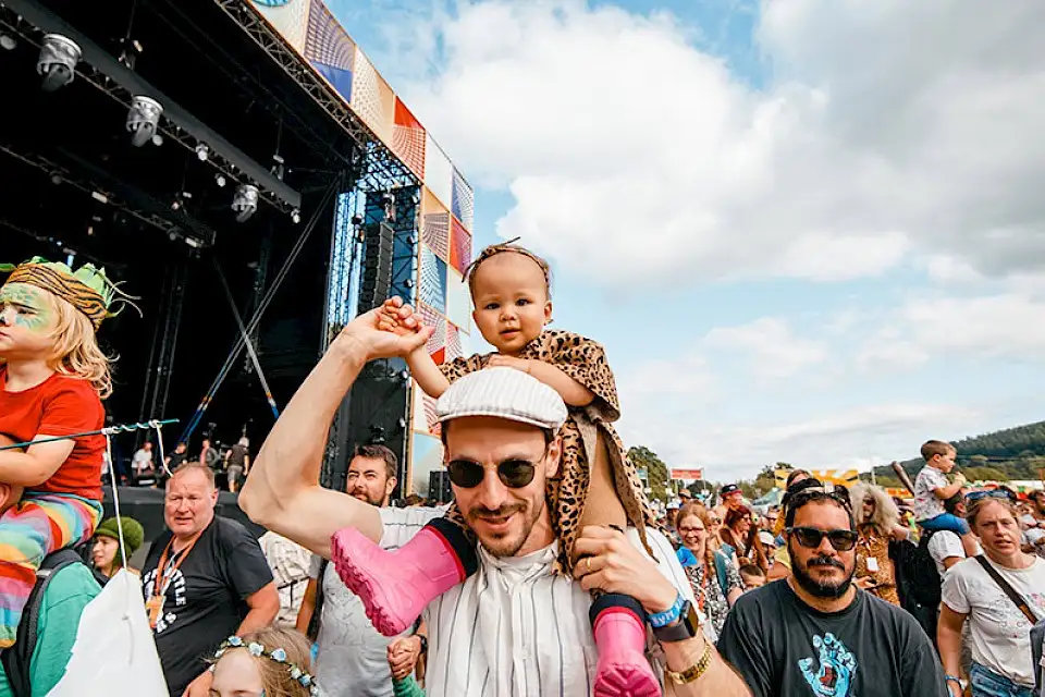 A man carries a small child on his shoulders in the Little Folk parade